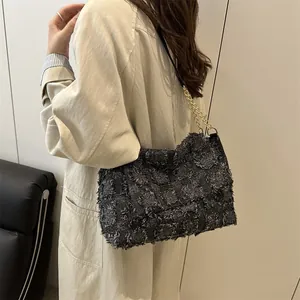 Chic dark gray tweed crossbody bag with gold chain strap shown on a model in minimalist room