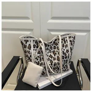 Detailed view of leopard print tote bag with small accessory pouch on a black chair