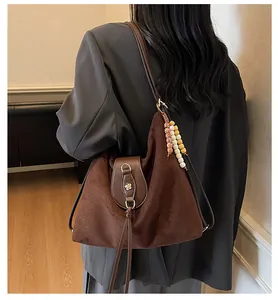 Détail du grand sac en daim marron avec rivet floral et pendentif ethnique à perles
