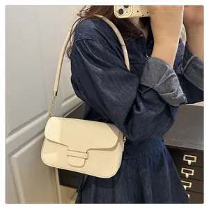 Close-up of minimalist cream leather crossbody bag with metallic chain strap detail