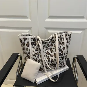 Leopard print canvas tote bag with white leather straps and matching pouch on a chair
