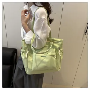 Detail of light green nylon tote bag featuring multi-pocket design and dual straps