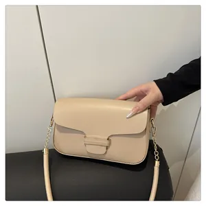 Close-up of cream square handbag with gold chain strap and elegant flap buckle