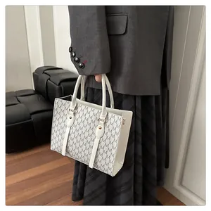 Detail of white tote bag with grey M-letter pattern and gold metal hardware clips