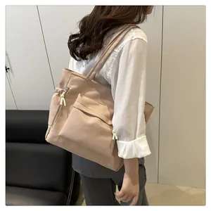 Detail of apricot tote bag featuring large front zipper pocket and white rope pulls
