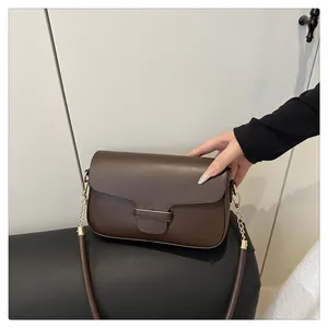 Close-up of deep brown leather shoulder bag with golden metal chain strap connectors