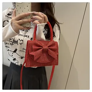 Détail du sac de soirée rouge pailleté avec un grand nœud et une texture scintillante