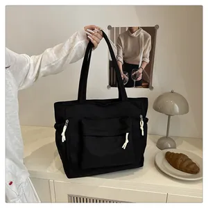 Detail of black nylon tote bag with white knot zippers and side pockets in a lifestyle setting