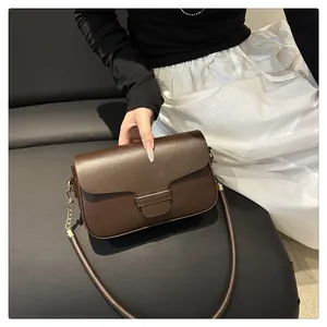Detailed close-up of dark brown leather handbag featuring a vintage flap and gold metal chain