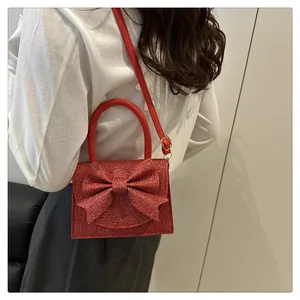 Vue latérale de la pochette rouge pailletée avec nœud portée en sac bandoulière