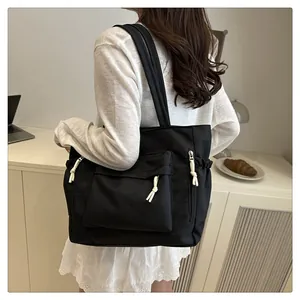 Detail of black large tote bag with front flap pocket and white knot zipper pulls