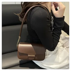 Detailed side view of a brown leather shoulder bag with gold chain strap on a model