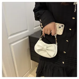 Close-up of mini white handbag with large bow and pearl handle held by a model