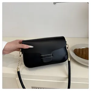 Detailed close-up of a black leather shoulder bag featuring gold chain and metal bar accents