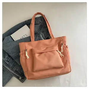 Detail of pink tote bag showing front zipper pocket and functional side elastic pockets