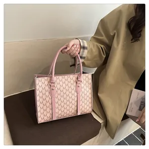 Close-up of pink tote bag featuring letter pattern and gold rivet handle details