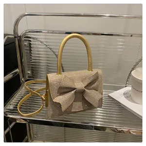 Détail d'un sac à main pailleté doré avec un nœud papillon sur une étagère