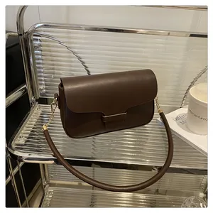 Dark brown matte leather bag on a minimalist shelf with a coffee cup and books