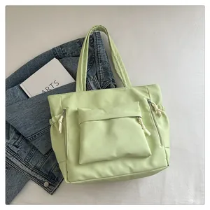 Detail of mint green tote bag featuring multiple zip pockets and white knotted pullers