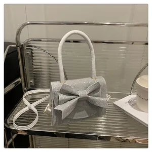 Détail du sac à paillettes argentées avec grand nœud et poignée en cuir blanc élégante