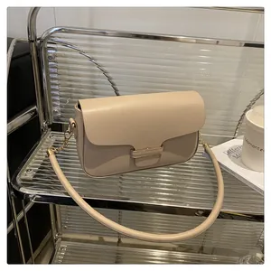 Detail of beige rectangular crossbody bag with metallic buckle and gold chain strap