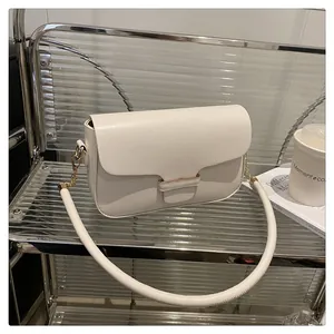 Detail view of the white leather handbag featuring a gold metal buckle and tubular strap