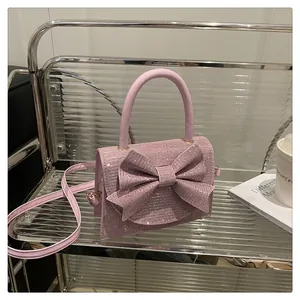 Détail du mini sac rose clair pailleté avec grand nœud et finitions dorées