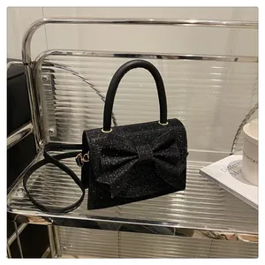 Détail macro d'un sac à main noir pailleté avec un grand nœud et une poignée supérieure