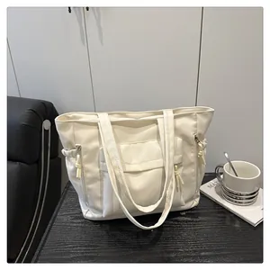 Detail of cream tote bag with large front flap pocket on a minimalist black wooden table