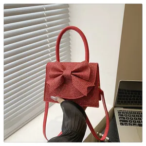 Détail du sac à main rouge à paillettes avec grand nœud et bandoulière amovible
