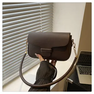 Close-up of a small chocolate brown leather shoulder bag with gold chain strap detail