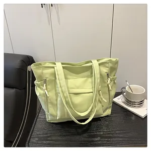 Detail of avocado green tote bag with multiple pockets and drawstring on wood desk