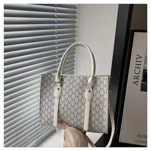 Macro shot of white M-letter printed tote bag showing leather texture and strap details