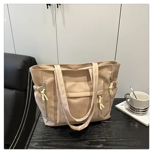 Macro shot of beige tote bag with functional zippers and side pockets on a desk