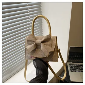 Gros plan sur le sac à main pailleté doré champagne avec nœud et poignée ronde