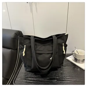 Detail of black nylon tote bag with functional zipper pockets and white cord pulls