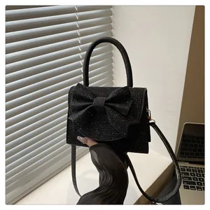 Vue détaillée du sac à main à paillettes noires avec grand nœud et poignée ronde