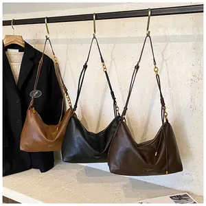 Detailed view of three vintage-style half-moon hobo bags in brown, black, and dark coffee