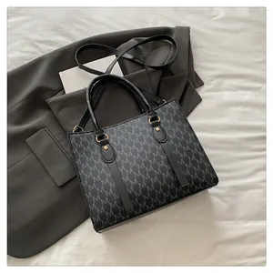 Detailed view of women's tote bag with M-letter pattern on textured gray blazer