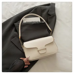 Detail of cream leather shoulder bag with gold chain strap and metal bar buckle