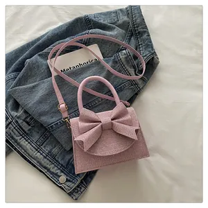 Gros plan d'un mini sac en tweed rose avec nœud sur une veste en jean
