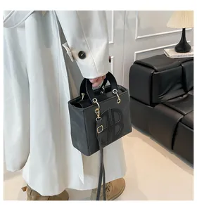 Détail du sac bandoulière en cuir noir avec logo embossé et finitions dorées