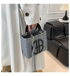 Détail du sac à main en feutre gris avec logo HB noir et accents en métal doré