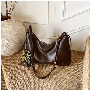 Detail of dark brown retro shoulder bag featuring a leopard print charm and gold hardware