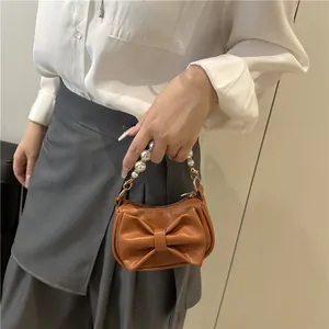 Brown mini square bag with ribbon bow, white pearl handle, and gold metal hardware