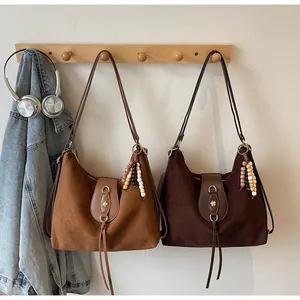 Détail du sac à bandoulière en daim marron avec breloque en bois et boucle en cuir élégante