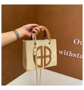 Détail du sac en toile avec monogramme en cuir marron et boucles métalliques dorées