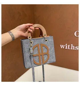 Détail d'un sac cabas en feutre gris avec garniture en cuir brun et boucles dorées