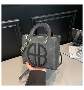 Détail de la texture cuir grainé et des ferrures dorées sur un sac à main noir