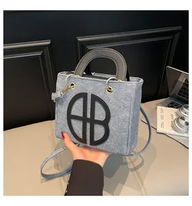 Détail d'un sac à main gris avec logo BB noir et finitions métalliques dorées